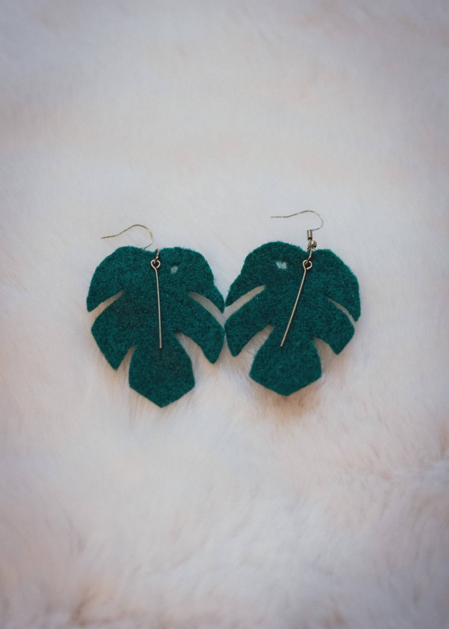 Jungle Monstera leaf felt earrings laying on a white background