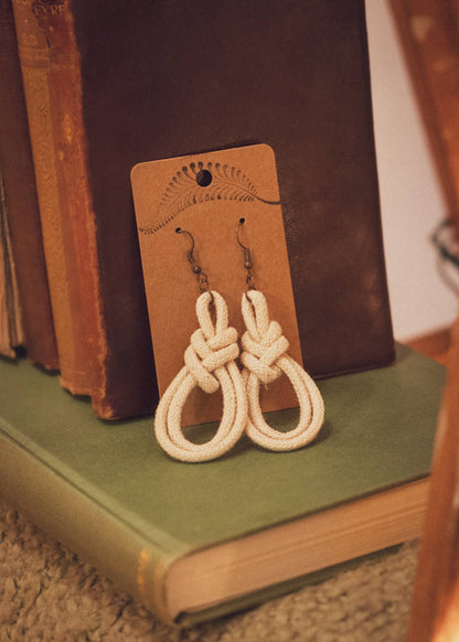 Double Macrame Loop earrings resting against some vintage books on a ladder blanket shelf