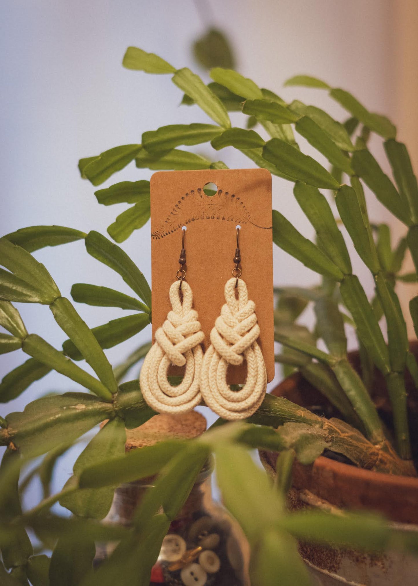 Triple Macrame Loop earrings resting gently against a happy Christmas Cactus house plant