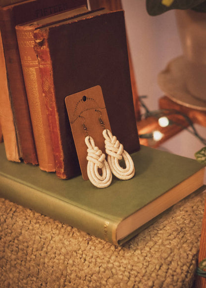 Triple Macrame Loop earrings resting against vintage books on a blanket ladder shelf